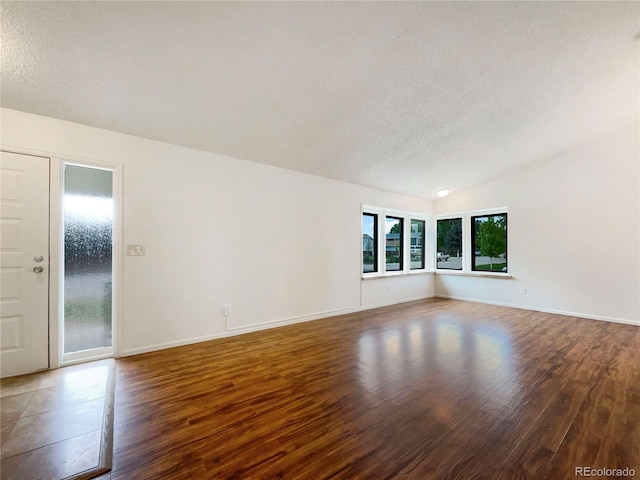 1460 Belmont Dr, Longmont, CO 80503 - empty room featuring a textured ceiling, wood finished floors, and vaulted ceiling