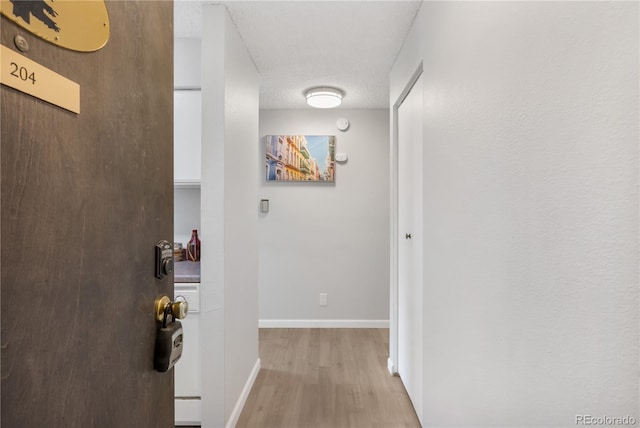 hall featuring a textured ceiling and light hardwood / wood-style floors