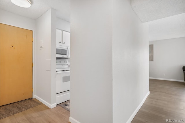 hall featuring light hardwood / wood-style floors and a textured ceiling