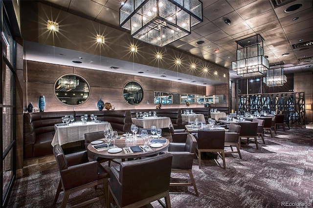 dining space with a towering ceiling, a notable chandelier, and carpet flooring