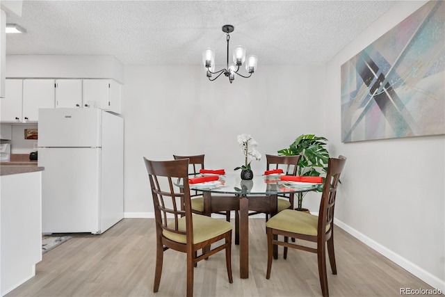 dining room with an inviting chandelier, a textured ceiling, and light wood-type flooring