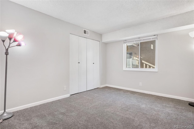 unfurnished bedroom with carpet flooring, a textured ceiling, and a closet