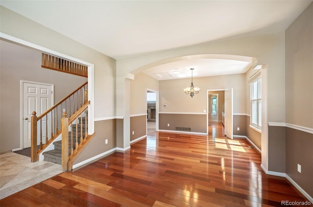 15577 Greenstone Cir, Parker, CO 80134 - empty room featuring arched walkways, hardwood / wood-style floors, a chandelier, and stairway