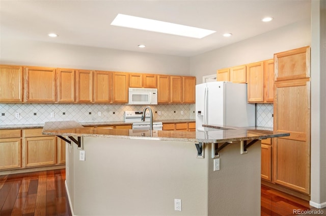 15577 Greenstone Cir, Parker, CO 80134 - kitchen featuring white appliances, an island with sink, light stone countertops, dark wood finished floors, and recessed lighting