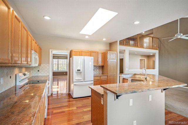 15577 Greenstone Cir, Parker, CO 80134 - kitchen with white appliances, a breakfast bar, light wood-style flooring, a skylight, and recessed lighting