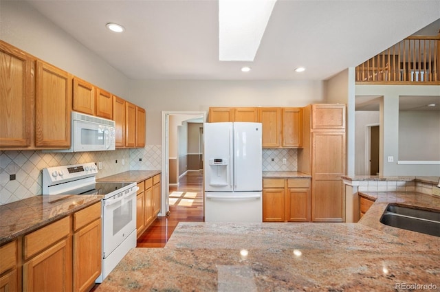 15577 Greenstone Cir, Parker, CO 80134 - kitchen featuring white appliances, a skylight, light stone counters, wood finished floors, and recessed lighting