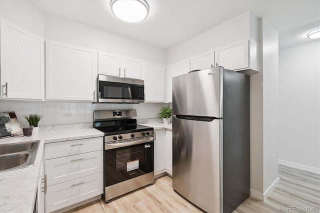 660 S Alton Way Unit 12C, Denver, CO 80247 - kitchen with stainless steel appliances, white cabinetry, light wood-style flooring, and backsplash