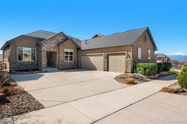 6203 Adamants Dr, Colorado Springs, CO 80924 - view of front of house featuring a garage, stucco siding, stone siding, a mountain view, and driveway