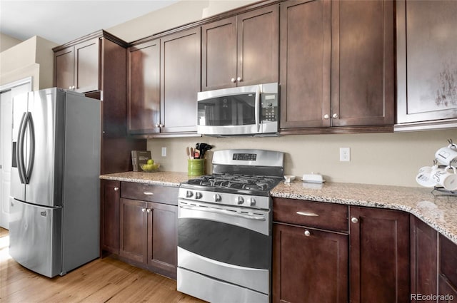 6203 Adamants Dr, Colorado Springs, CO 80924 - kitchen featuring light wood-type flooring, dark brown cabinetry, light stone counters, and stainless steel appliances