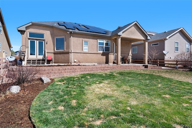 6203 Adamants Dr, Colorado Springs, CO 80924 - rear view of property with roof mounted solar panels, entry steps, a lawn, fence, and stucco siding