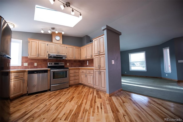 kitchen with stainless steel appliances, light brown cabinetry, light countertops, and under cabinet range hood