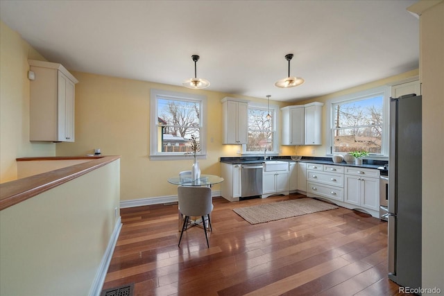 3764 Newton St, Denver, CO 80211 - kitchen with stainless steel appliances, baseboards, hardwood / wood-style flooring, decorative light fixtures, and white cabinets