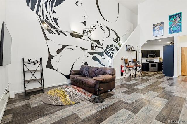 living area with wood finished floors, a towering ceiling, and baseboards