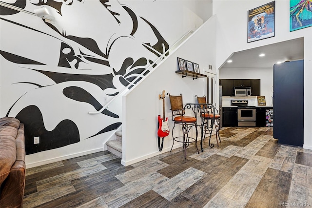 foyer with wood finished floors, stairs, a high ceiling, baseboards, and recessed lighting