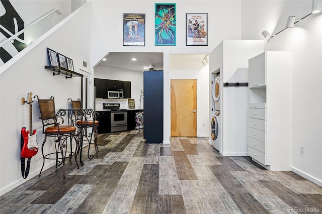 entryway featuring estacked washer and dryer, a high ceiling, dark wood-style flooring, baseboards, and recessed lighting