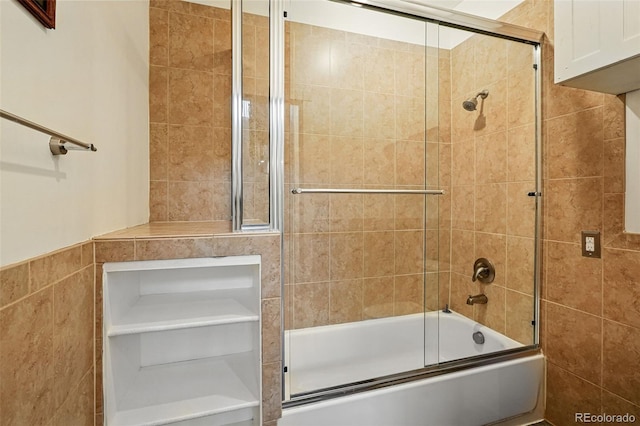 full bath with tile walls and bath / shower combo with glass door
