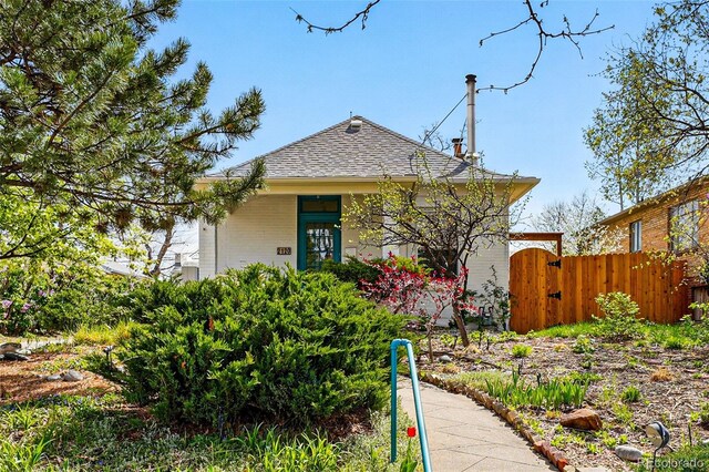 bungalow-style house featuring brick siding, a shingled roof, fence, and a gate
