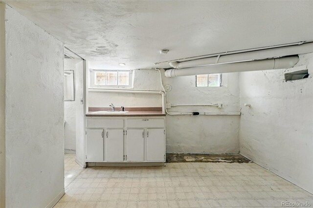 basement with a sink and light floors