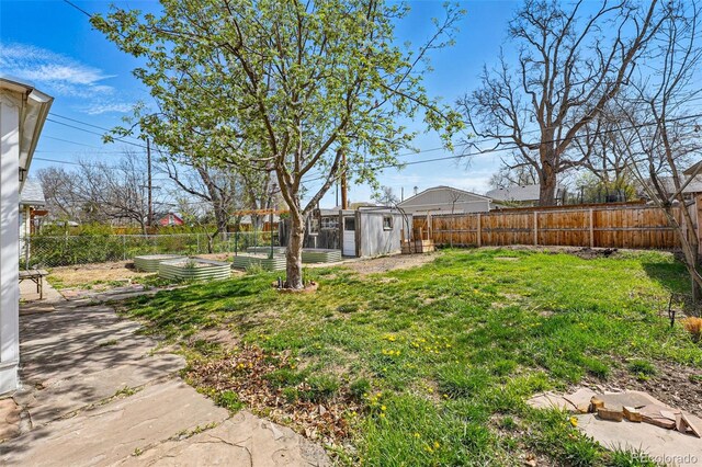 view of yard with a storage unit, an outdoor structure, a fenced backyard, and a vegetable garden