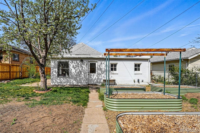 back of house featuring fence and a garden