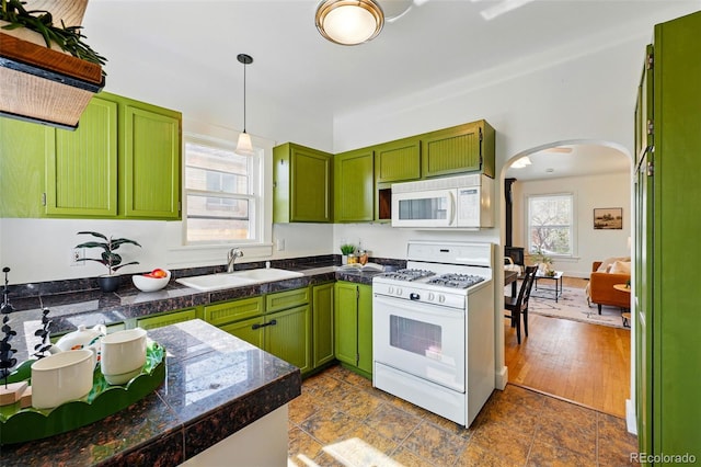 kitchen featuring white appliances, tile counters, green cabinetry, arched walkways, and a sink