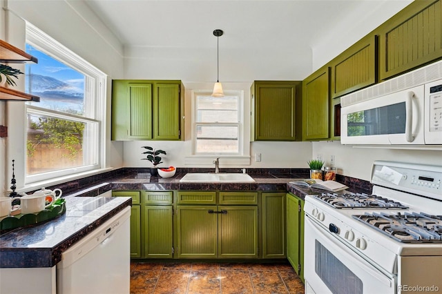 kitchen with green cabinetry, a sink, white appliances, tile countertops, and a wealth of natural light