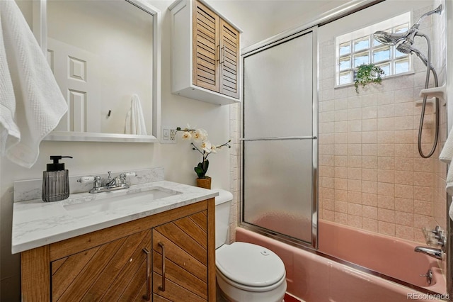 full bathroom featuring toilet, bath / shower combo with glass door, and vanity