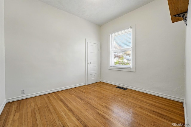 unfurnished room featuring baseboards, visible vents, and light wood finished floors