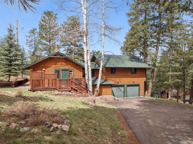 27905 Mariposa Rd, Evergreen, CO 80439 - view of front facade with a garage, a wooden deck, and aphalt driveway