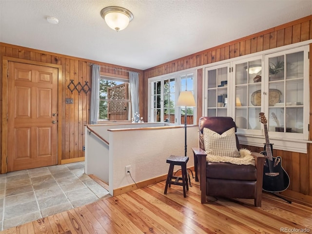 27905 Mariposa Rd, Evergreen, CO 80439 - living area featuring baseboards, wood walls, light wood-style flooring, and a textured ceiling