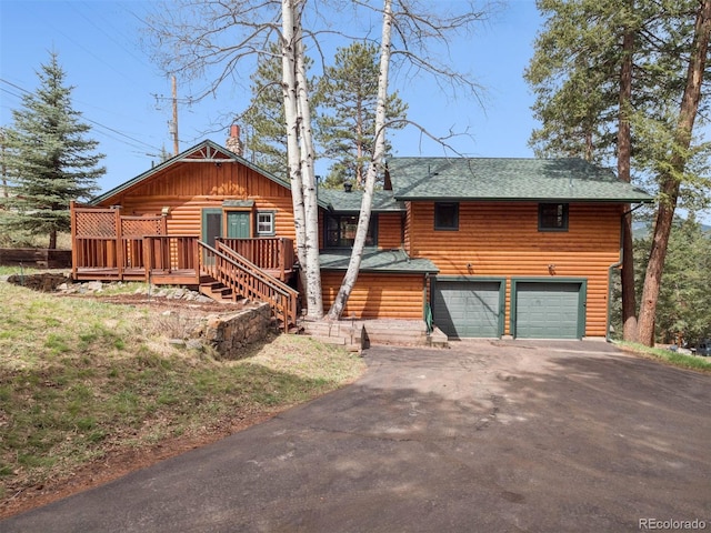 27905 Mariposa Rd, Evergreen, CO 80439 - log home featuring a deck, aphalt driveway, an attached garage, a shingled roof, and stairs