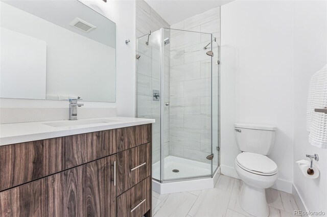 bathroom featuring vanity, a shower with shower door, and toilet