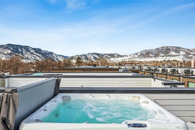 snow covered deck featuring washer / clothes dryer, a mountain view, and a hot tub