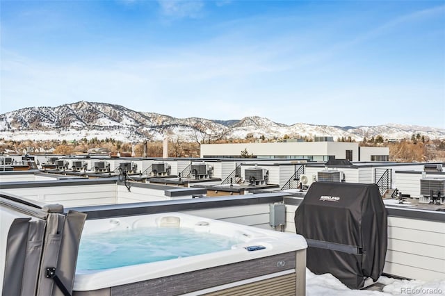 snow covered deck featuring a mountain view, a hot tub, and a grill