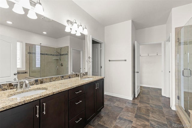 2423 Delicato Ct, Colorado Springs, CO 80921 - bathroom with a stall shower, double vanity, baseboards, a spacious closet, and stone finish flooring