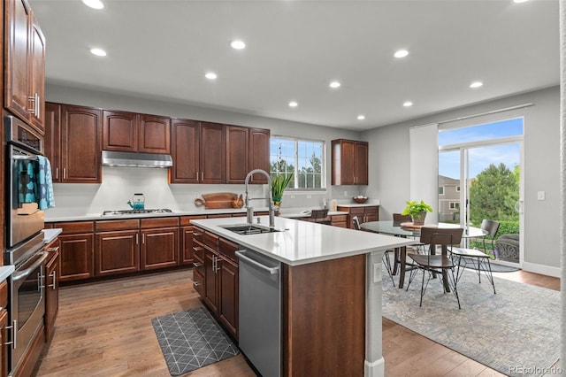 5984 S Paris Pl, Greenwood Village, CO 80111 - kitchen featuring appliances with stainless steel finishes, recessed lighting, light countertops, a kitchen island with sink, and light wood-type flooring