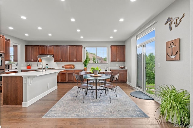 5984 S Paris Pl, Greenwood Village, CO 80111 - kitchen featuring light countertops, an island with sink, recessed lighting, dark wood-type flooring, and a kitchen breakfast bar