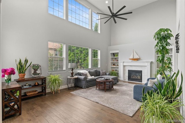 5984 S Paris Pl, Greenwood Village, CO 80111 - living area with a towering ceiling, a glass covered fireplace, ceiling fan, hardwood / wood-style floors, and built in features