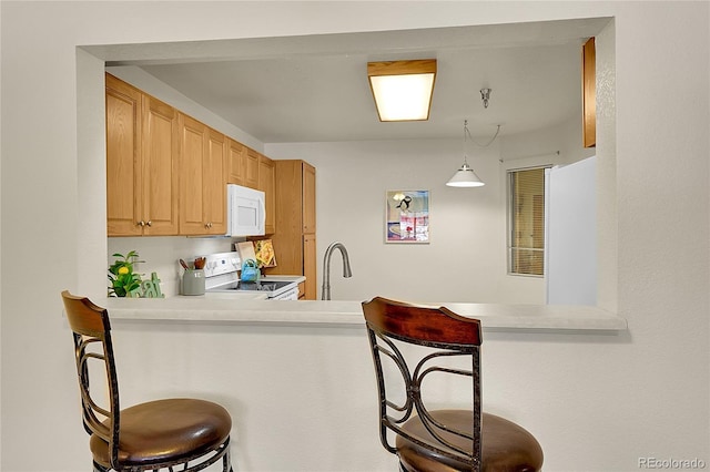 kitchen with kitchen peninsula, light brown cabinets, decorative light fixtures, a kitchen breakfast bar, and white appliances