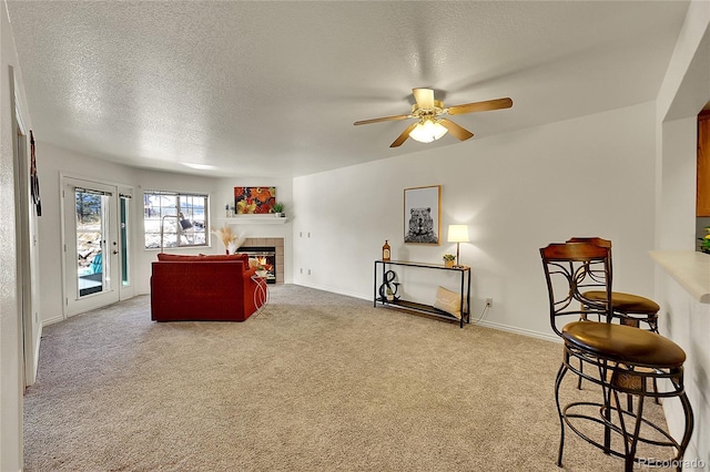 carpeted living room featuring ceiling fan, a textured ceiling, and a fireplace