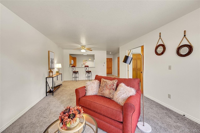 living room with carpet floors, ceiling fan, and a textured ceiling