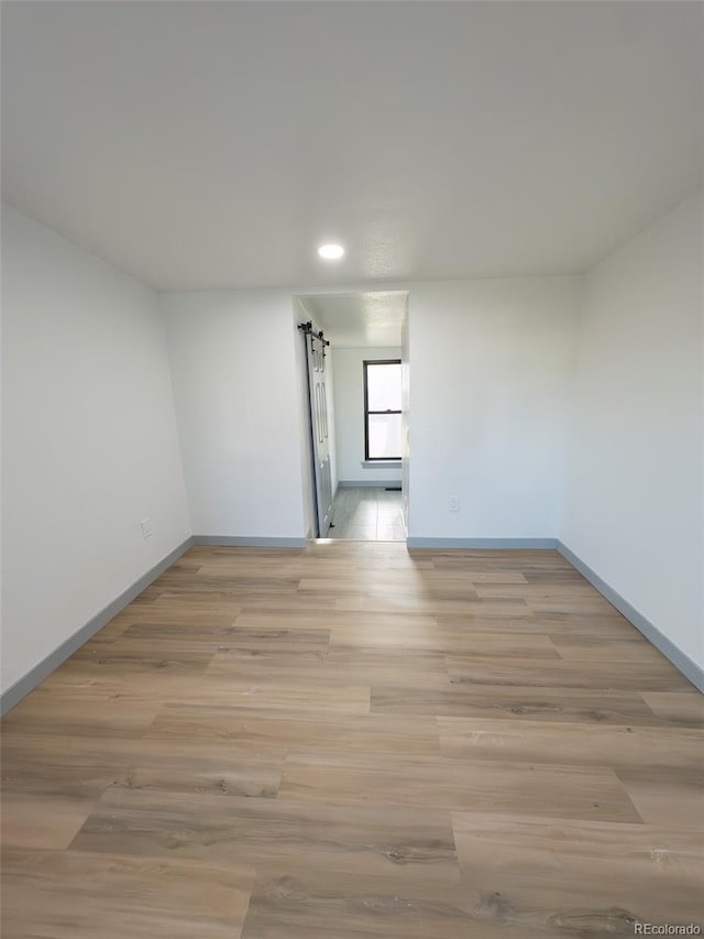 4476 S Grant St, Englewood, CO 80113 - empty room featuring baseboards, recessed lighting, light wood-style floors, and a barn door