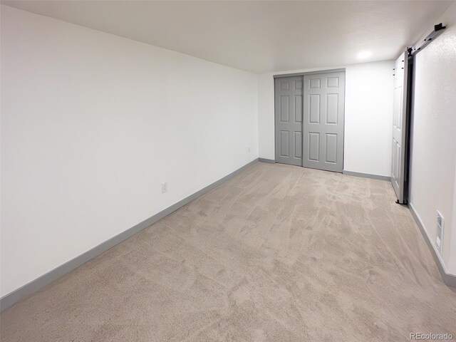 4476 S Grant St, Englewood, CO 80113 - unfurnished bedroom with a barn door, visible vents, a closet, baseboards, and light colored carpet