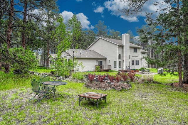 18470 Canterbury Dr, Monument, CO 80132 - back of house with an outdoor fire pit, a chimney, and a yard