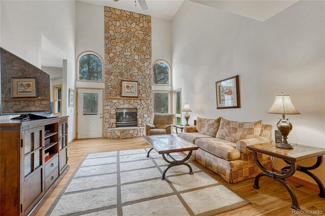 18470 Canterbury Dr, Monument, CO 80132 - living area with a towering ceiling, a stone fireplace, light wood-style flooring, and a ceiling fan