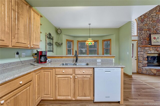 18470 Canterbury Dr, Monument, CO 80132 - kitchen featuring white dishwasher, light wood-style flooring, light countertops, a stone fireplace, and decorative light fixtures