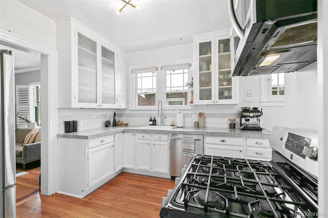 kitchen featuring white cabinets, extractor fan, stainless steel appliances, sink, and light wood-type flooring