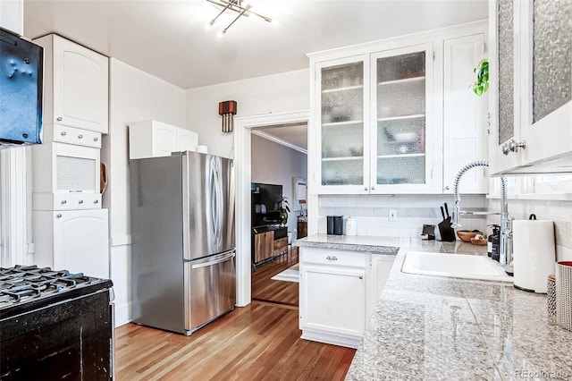 525 N Pearl St, Denver, CO 80203 - kitchen featuring freestanding refrigerator, glass insert cabinets, a sink, white cabinetry, and light wood-style floors