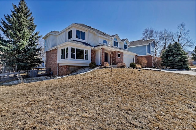 view of front of property featuring brick siding, a garage, and fence