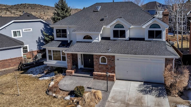 view of front of house featuring a chimney, brick siding, driveway, and a shingled roof